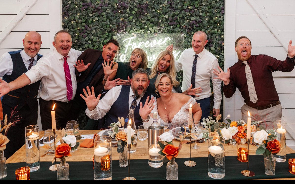 A bride and groom pulling silly faces with their guests at the top table