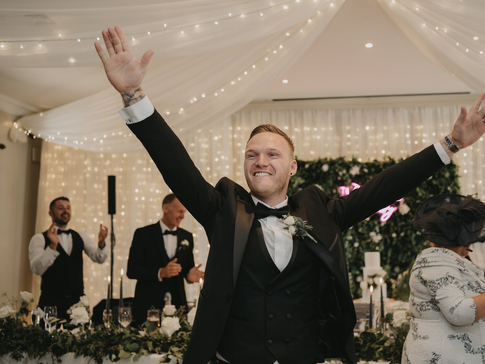 A groom throwing his arms wide during a grand entrance as guests cheer