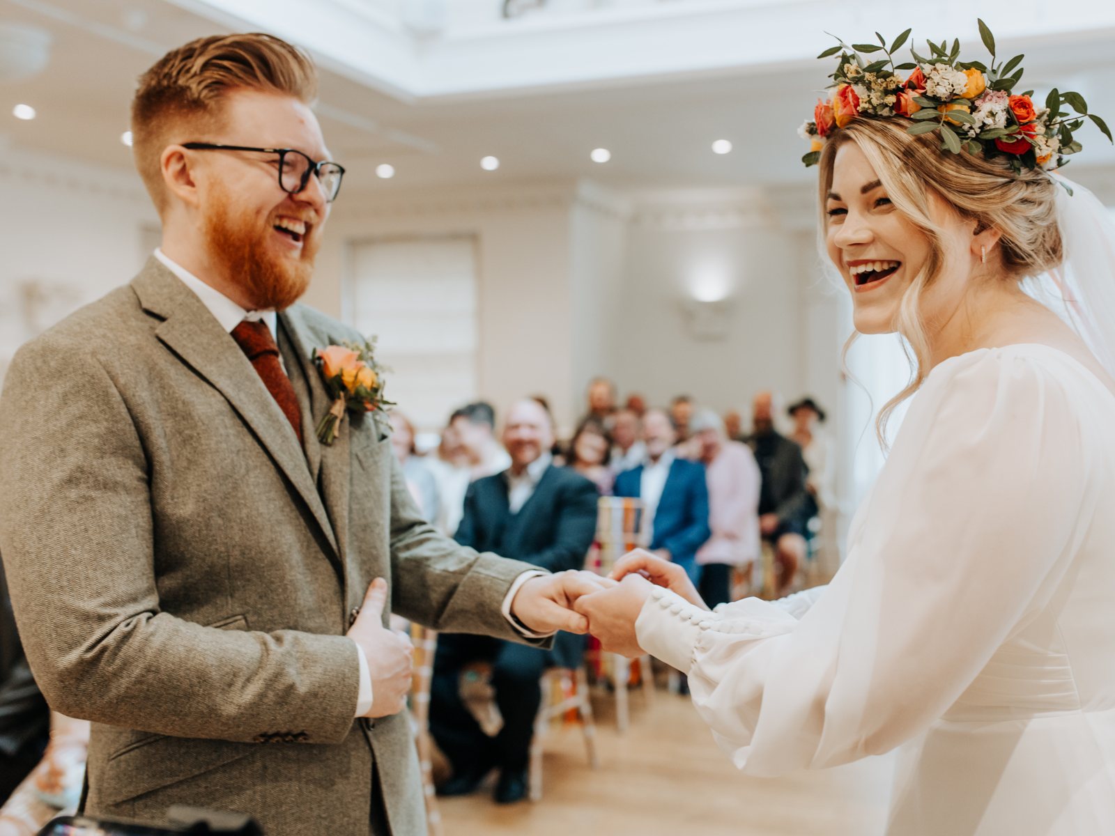 A bride and groom laughing as they hold hands during their ceremony