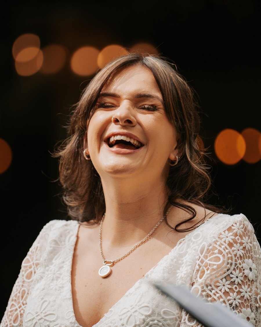 A bride with her eyes closed, laughing her head off during the ceremony